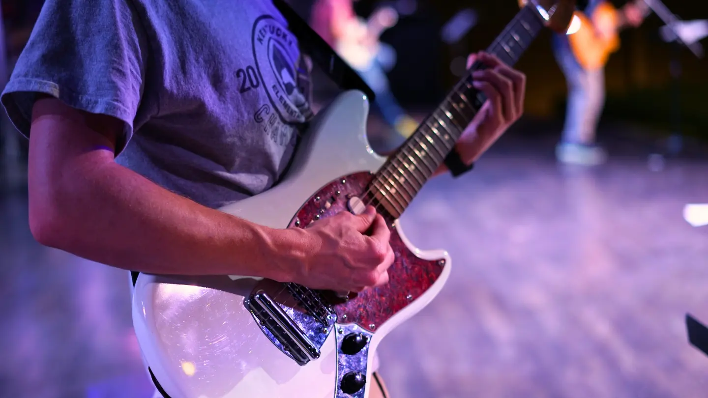 Close up on Jonah's hands playing guitar in the worship team