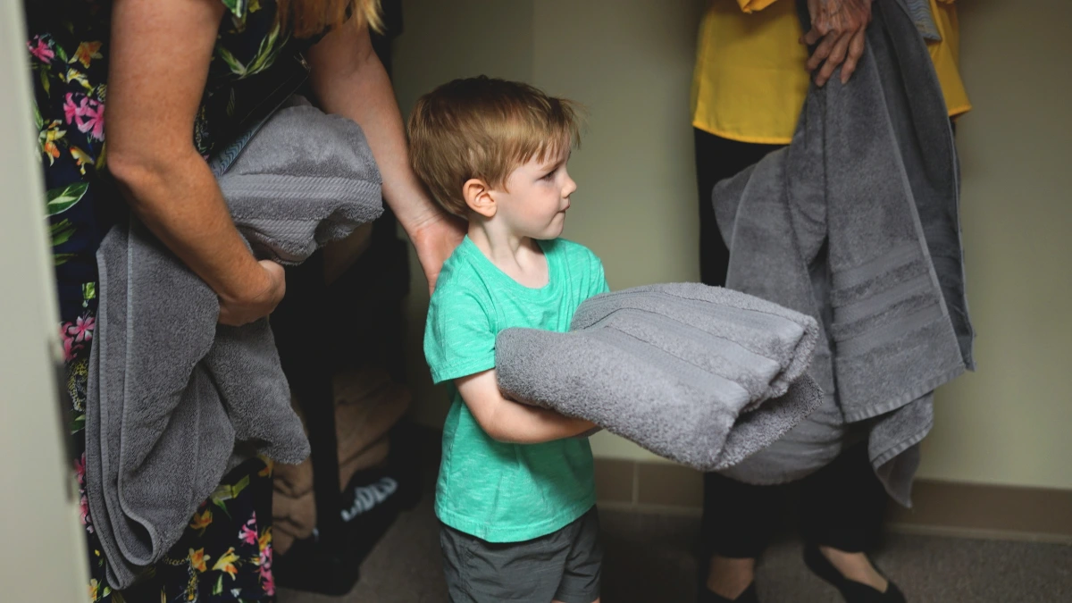 toddler holding towel to give to someone after being baptized