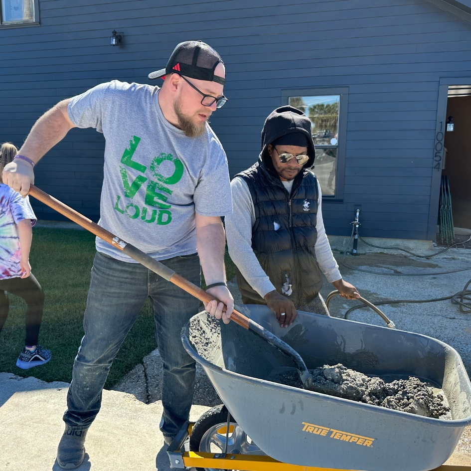 Pastor helping scoop concrete from wheelbarrow