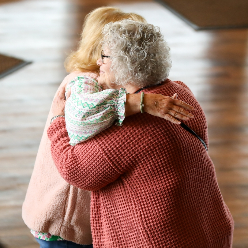 Women hugging in church lobby